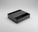 Black rectangular box on a concrete floor with a cardboard background