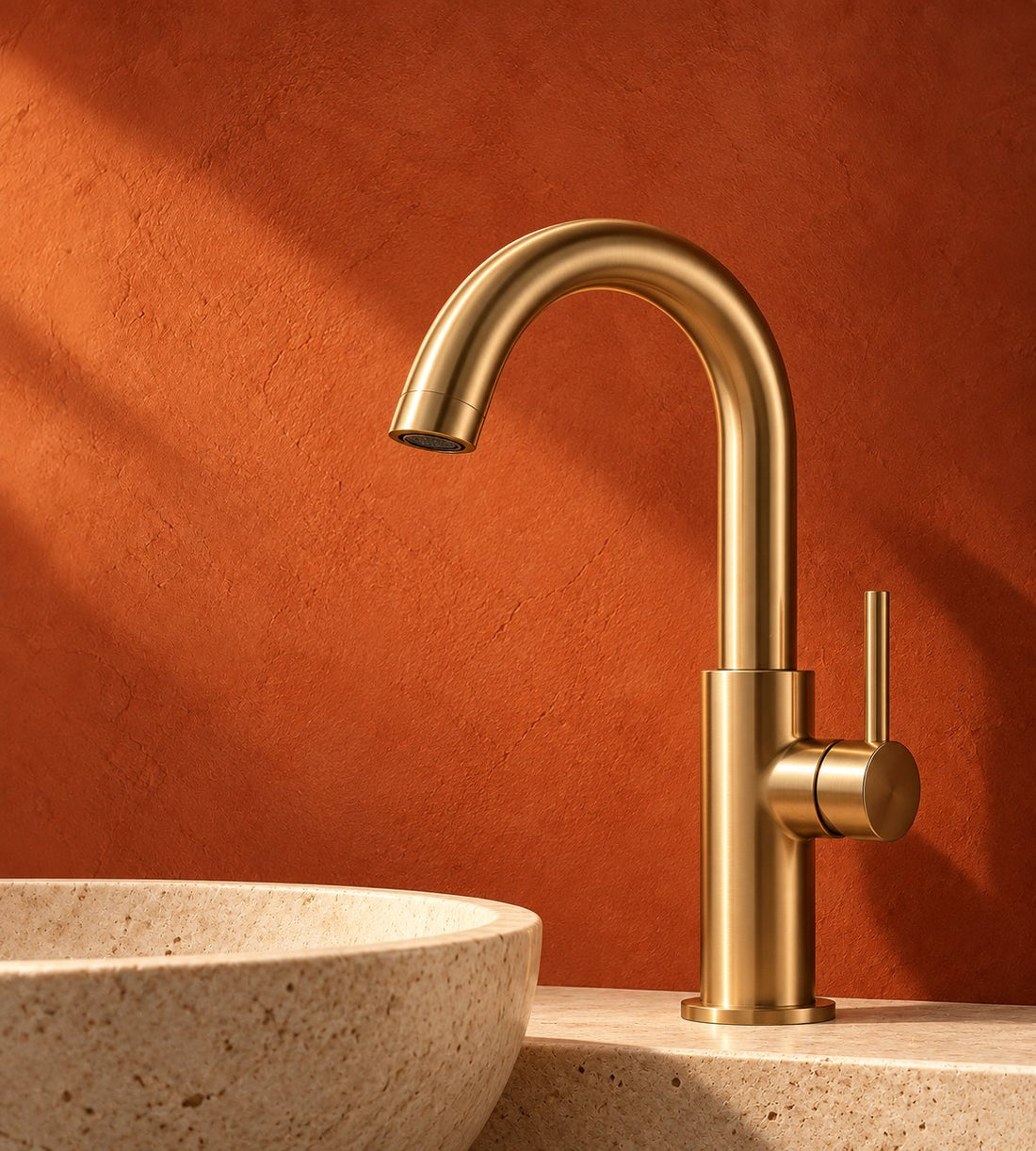 Brushed brass faucet against a terracotta wall